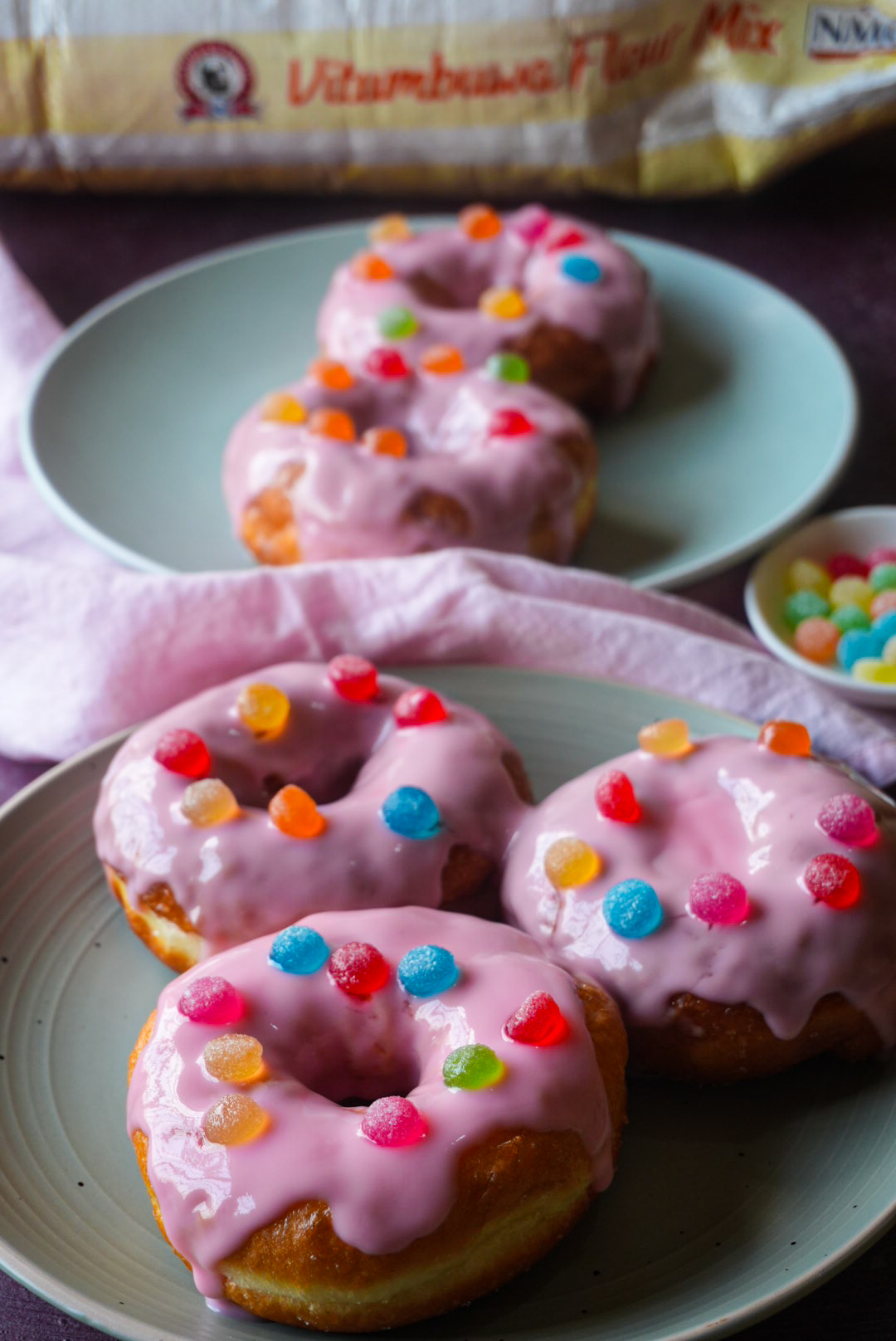 Pink glazed doughnuts plated with gum drops and Zambia's Pride flour mix packaging