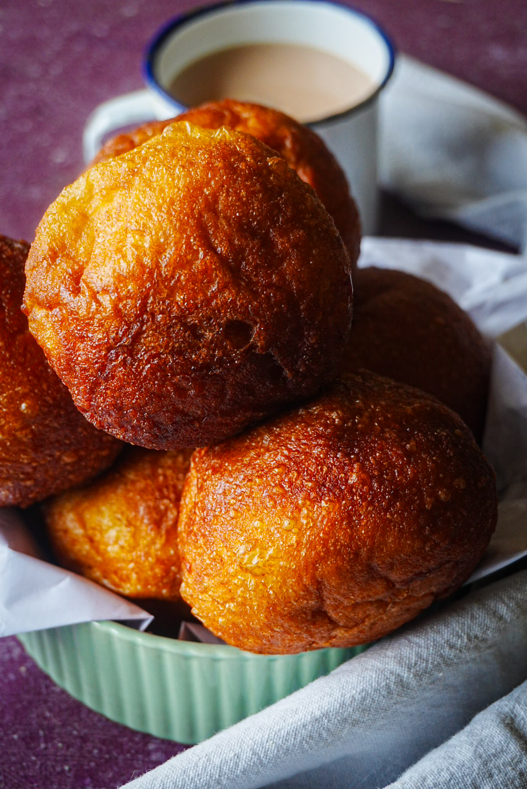 Fried doughnuts stacked in a bowl, styled with a cup of tea for National Milling Corporation